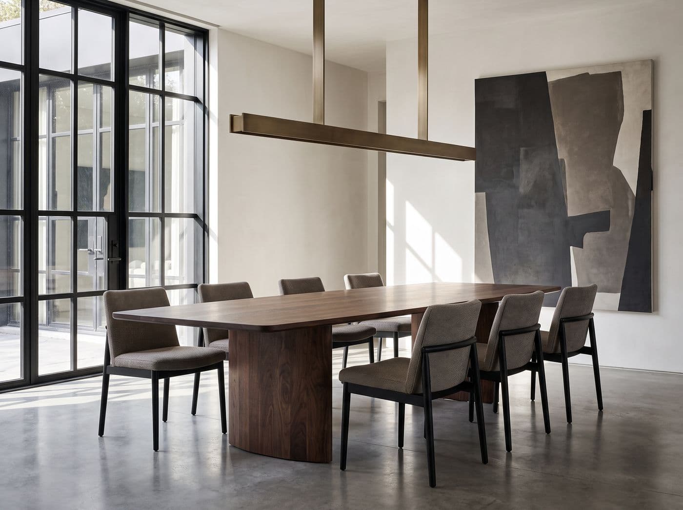 Contemporary dining room with a solid walnut pedestal table and a bronze linear pendant